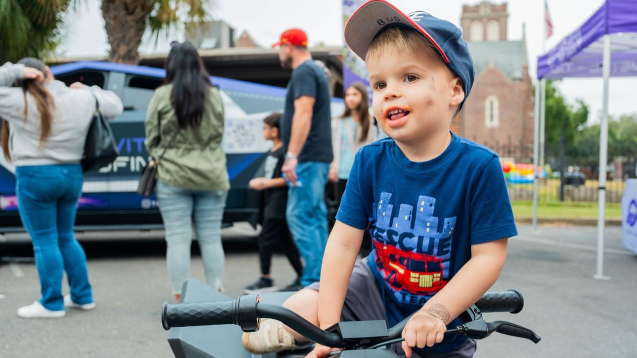A young boy enjoying Touch-A-Truck 2025 in Orlando, Florida with Gravity Roofing’s Gravitron vehicle in the background at Trinity Downtown